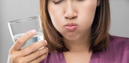 Woman rinsing and gargling while using mouthwash from a glass, During daily oral hygiene routine, Girl in a purple silk robe, Dental Healthcare Concepts