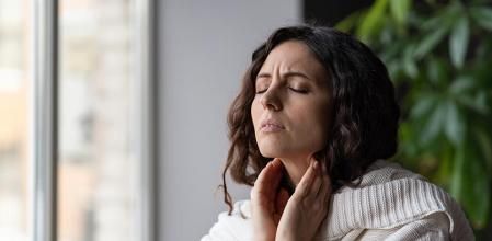 Una mujer se palpa los ganglios linfáticos de su cuello