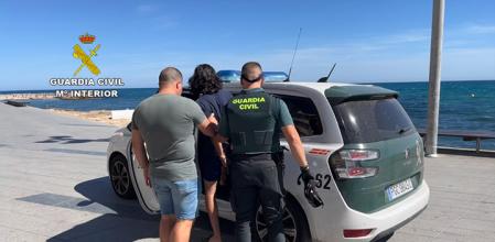 La Guardia Civil introduce en un coche a un detenido.