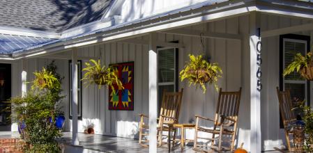 White Springs, Florida - November 24, 2021: Hanging ferns, wooden rocking chairs, colorful art, and a collection of pumpkins create an inviting seasonal look for the front porch of a renovated wood-frame house in the historic center of town.