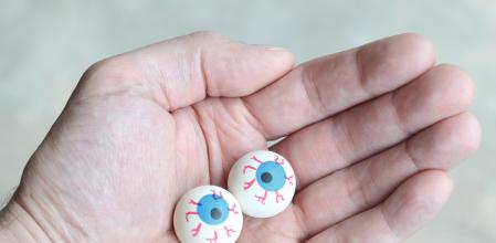 Close up of a man holding balls made to look like eyeballs in the palm of his hand for Halloween.