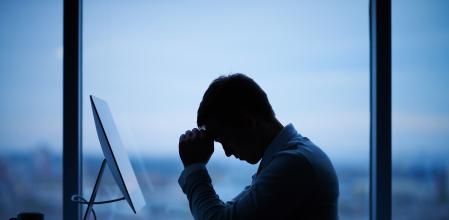 Tired or stressed businessman sitting in front of computer in office
