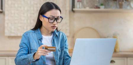Mujer asiática enfadada frente a tarjeta y ordenador