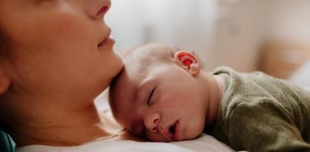 Photo of a young mother holding her newborn baby, while putting him to sleep