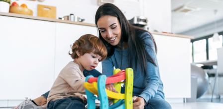 Shot of young beautiful mother playing on the floor with her son in living room at home.