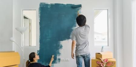 Young asian couple painting interior wall with paint roller in new house