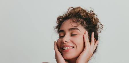 Portrait of a beautiful young woman with curly hair without make-up, studio shot in front of white background