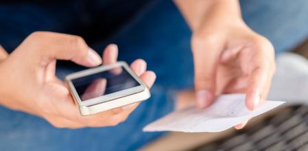 Woman use the mobile phone to calculate the bill on the other hand