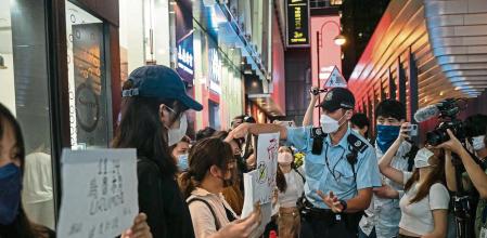 HONG KONG, CHINA - NOVEMBER 28: People hold signs in protest of COVID restriction in mainland as police setup cordon during a vigil in the central district on November 28, 2022 in Hong Kong, China. Protesters took to the streets in multiple Chinese cities after a deadly apartment fire in Xinjiang province sparked a national outcry as many blamed COVID restrictions for the deaths. (Photo by Anthony Kwan/Getty Images)