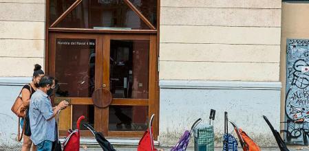 VARIAS PERSONAS HACEN COLA TRAS LOS CARROS A LA ESPERA QUE LES OFREZCAN AYUDA ALIMENTARIA EN UNA PARROQUIA DE LA RAMBLA DEL RAVAL