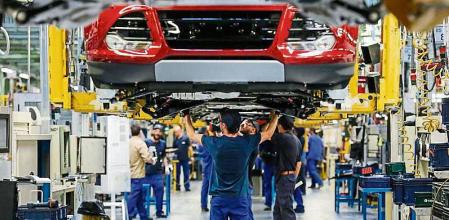 Employees work on the chassis assembly of automobiles as they pass along an overhead conveyor belt at the Ford Motor Co. plant in Almusafes, Spain, on Monday, April 18, 2016. Ford's Valencia plant is one of the most advanced, flexible and productive auto plants in the world according to a company statement. Photographer: Pau Barrena/Bloomberg