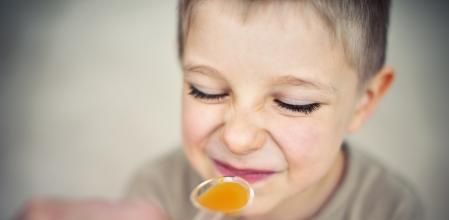 Little boy aged 4 taking a spoon of disgusting medicine.