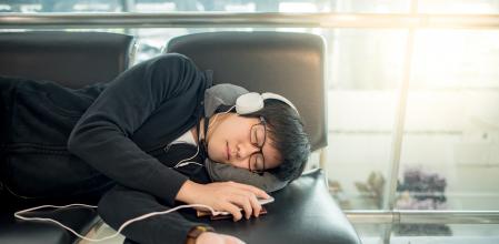 Un joven duerme con auriculares en un aeropuerto