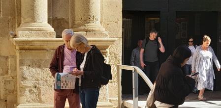 Dos turistas consultan un plano de Alicante ante la concatedral de San Nicolás.