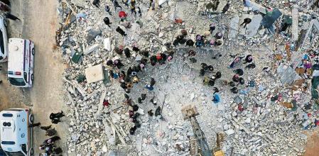 Civil defense workers and residents search through the rubble of collapsed buildings in the town of Harem near the Turkish border, Idlib province, Syria, Monday, Feb. 6, 2023. A powerful earthquake has caused significant damage in southeast Turkey and Syria and many casualties are feared. Damage was reported across several Turkish provinces, and rescue teams were being sent from around the country. (AP Photo/Ghaith Alsayed)