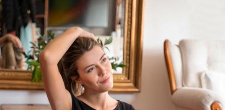 Young Latin American woman stretching her neck before exercising at home and sitting on a mat – healthy lifestyle concepts