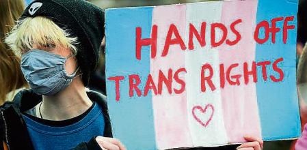 A Trans Rights activist holds a placard while taking part in the