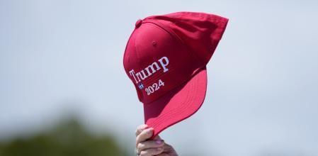 Un seguidor de Trump agita una gorra de su campaña delante de su casa deMar-a-Lago, en Florida
