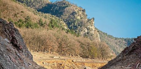 ACTUAL ESTADO DE ALMACENAMIENTO DE AGUA DEL EMBALSE DE LA BAELLS QUE ESTA AL 26% Y PERTENECE A LAS AGUAS DEL RIO LLOBREGAT. UN CICLISTA ATRAVIESA UNA ZONA QUE DEBERIA ESTAR CUBIERTA POR EL AGUA