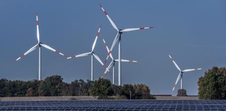 FILE - Wind turbines turn behind a solar farm in Rapshagen, Germany, Oct. 28, 2021. Germany is shutting down its last three nuclear power plants on Saturday, April 15, 2023, as part of an energy transition agreed by successive governments and the price of installing solar and wind energy has dropped significantly in recent years. (AP Photo/Michael Sohn, File)