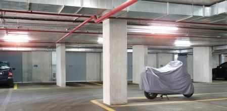 Una moto cubierta con una funda está aparcada en un parking