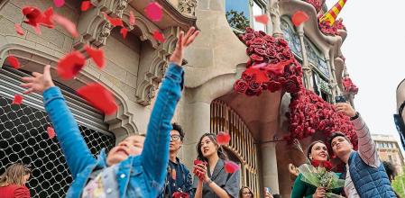 Ambiente en las calles de Barcelona de la Diada de Sant Jordi en la venta de libros y rosas. La casa Batllo decorada con rosas sirve para hacerse selfies a toda la gente que pasea por la fachada. Una niña juega con los pétalos de rosas del suelo, junto al edificio