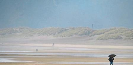 SALINAS (ASTURIAS), 21/05/2023.- Personas caminan por la playa en una mañana con bruma y humedad. La Aemet prevé para la jornada de hoy intervalos nubosos aumentando a nuboso con lluvias débiles y chubascos dispersos más probables y frecuentes en el interior y por la tarde. Probables brumas o nieblas dispersas en cotas altas de la Cordillera al principio y final del día. Temperaturas mínimas en descenso, más acusado en el sur. Temperaturas máximas con cambios ligeros predominando los aumentos. Heladas débiles y dispersas en cumbres de la Cordillera. Vientos flojos variables con predominio del nordeste en las horas centrales del día. EFE/Eloy Alonso