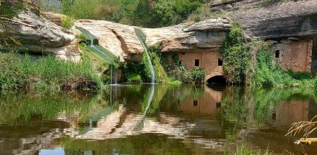 La simetría del Molí d'en Brotons en el reflejo del agua.
