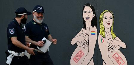 TOPSHOT - Local police officers walk past a mural painting made by Italian artist and activist aleXsandro Palombo, depicting Prime Minister Giorgia Meloni (R) and Democratic Party (PD) Secretary Elly Schlein (L) naked and pregnant in reference to the ongoing debate over surrogacy in the country, in Milan on May 22, 2023. (Photo by GABRIEL BOUYS / AFP) / RESTRICTED TO EDITORIAL USE - MANDATORY MENTION OF THE ARTIST UPON PUBLICATION - TO ILLUSTRATE THE EVENT AS SPECIFIED IN THE CAPTION
