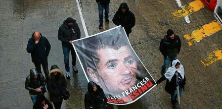 (FILES) Protesters hold a portrait of Yvan Colonna in Bastia on March 13, 2022 during a rally in hommage to the pro-independence activist after he was assaulted in the prison of Arles. The parliamentary commission investigating the death of Corsican independence activist Yvan Colonna in Arles prison in March 2022 has pointed to a series of 