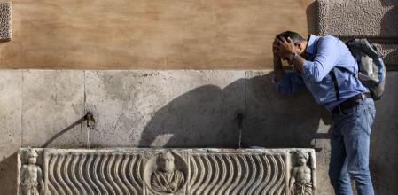 Un hombre se refresca en una fuente de Roma durante la ola de calor durante la jornada del 18 de julio