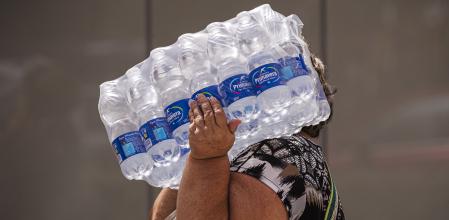 Una mujer lleva botellas de agua en la playa de la Malagueta (Málaga)