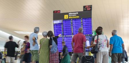 Un grupo de pasajeros consulta los vuelos en la T1 de El Prat