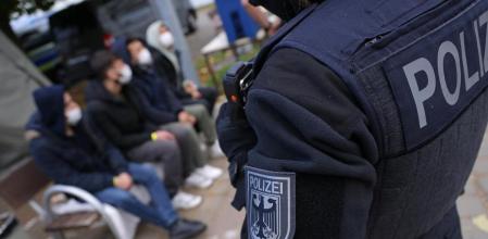FRANKFURT (ODER), GERMANY - OCTOBER 12: A German federal police officer stands over four men who said they are from Afghanistan who had crossed illegally into Germany across the border from Poland on October 12, 2021 in Frankfurt (Oder), Germany. Police are reporting a dramatic increase in the numbers of illegal migrants arriving in Germany from Poland, with over 800 arriving in the state of Brandenburg within the last week alone. Most of the migrants are originally from countries including Iran, Iraq and Yemen. Many are arriving via Belarus, which has allowed migrants from Iraq to fly to Belarus and let them try to reach neighboring countries in the European Union from there. (Photo by Sean Gallup/Getty Images)
