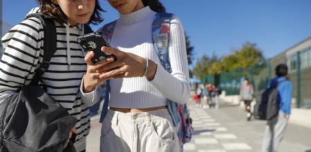ADOLESCENTES UTILIZANDO EL MOVIL A LA SALIDA DE UN INSTITUTO DE SANT CUGAT