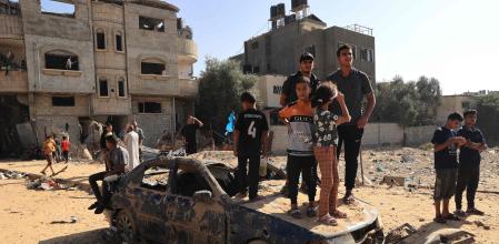 EDITORS NOTE: Graphic content / TOPSHOT - Palestinians stand on a destroyed vehicle as they watch rescuers search the debris of a building after an Israeli strike on Rafah, in the southern Gaza Strip on November 9, 2023, amid the ongoing battles between Israel and the Palestinian group Hamas. Since October 7, the Israeli military has been bombarding Gaza in retaliation for the Hamas attack that killed more than 1,400 people in Israel, most of them civilians, according to Israeli authorities. The Hamas-run health ministry says the death toll in Gaza has surpassed 10,500 people, mainly civilians and thousands of them children. (Photo by SAID KHATIB / AFP)