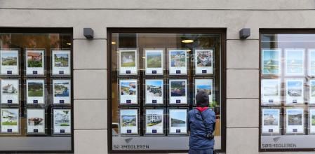 Una persona mira el aparador de una inmobiliaria a pie de calle