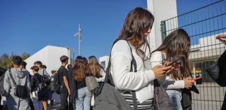 ADOLESCENTES UTILIZANDO EL MOVIL A LA SALIDA DE UN INSTITUTO DE SANT CUGAT