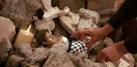 A woman arranges an installation of a scene of the nativity of Christ withith a figure