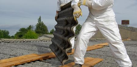 Un operari retira plaques de fibrociment d'una coberta