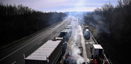 Protesting farmers gather with tractors to blockade the A16 highway, near Beauvais some hundred kilometers north of Paris, on January 28, 2024, part of a nationwide campaign of protests called by several farmers unions on pay, tax and regulations. Farmers have fumed at what they say is a squeeze on purchase prices for produce by supermarket and industrial buyers, as well as complex environmental regulations. (Photo by JULIEN DE ROSA / AFP)