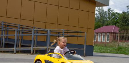 Una niña subida en un coche eléctrico infantil.