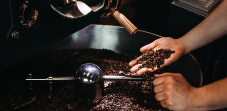 Las manos de un señor cogiendo granos de café tostado