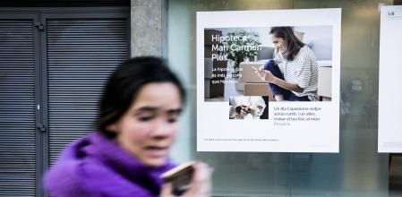 Una transeúnte pasa por delante del anuncio de la oferta hipotecaria de una entidad bancaria