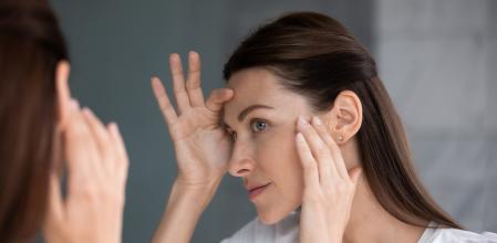 Una mujer mirándose al espejo mirando si tiene arrugas.
