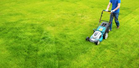 Una persona pasando el cortacésped por su jardín