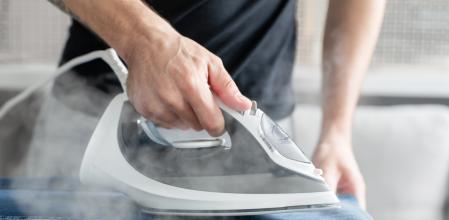 Una persona planchando la ropa con una plancha de vapor.