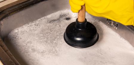 Una persona usando un desatascador de tuberías.