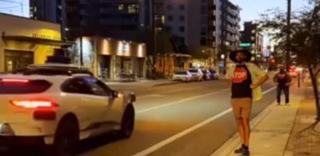 Un robotaxi se detiene junto al autor del experimento, que viste una camiseta con la señal de stop serigrafiada&nbsp;
