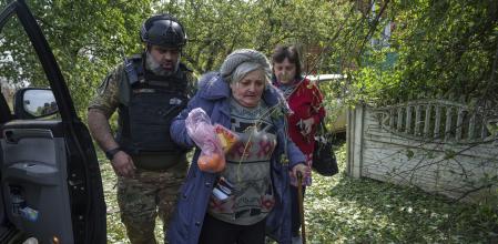 Volunteer Vitaliy Kylchik helps Valentyna to walk to a car during evacuation to Kharkiv, in Vovchansk, Ukraine, on Saturday, May 11, 2024. (AP Photo/Evgeniy Maloletka)